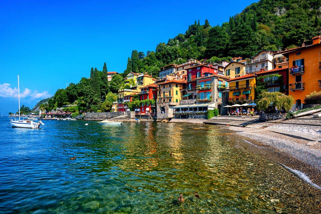 A town on Lake Como with a boat in the foreground and a clear blue sky.