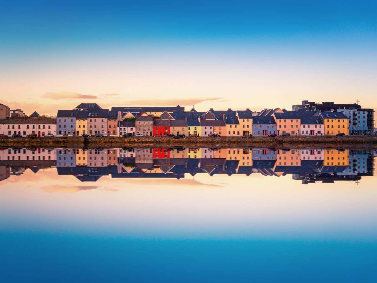 Vue sur es maisons colorées de Galway se reflétant dans l'eau, à la tombée de la nuit