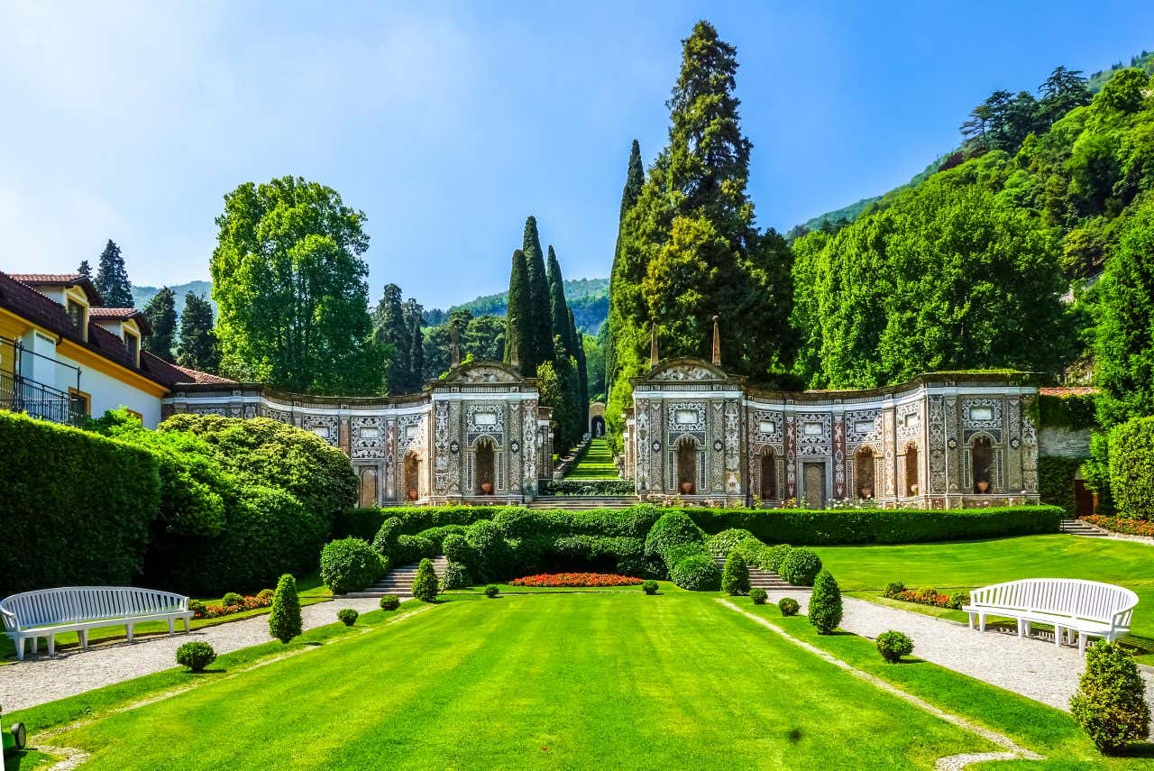 Giardini barocchi di Villa d'Este a Cernobbio in una giornata soleggiata, con aiuole geometriche, siepi scolpite e fontane decorative accostate alla storica facciata della villa