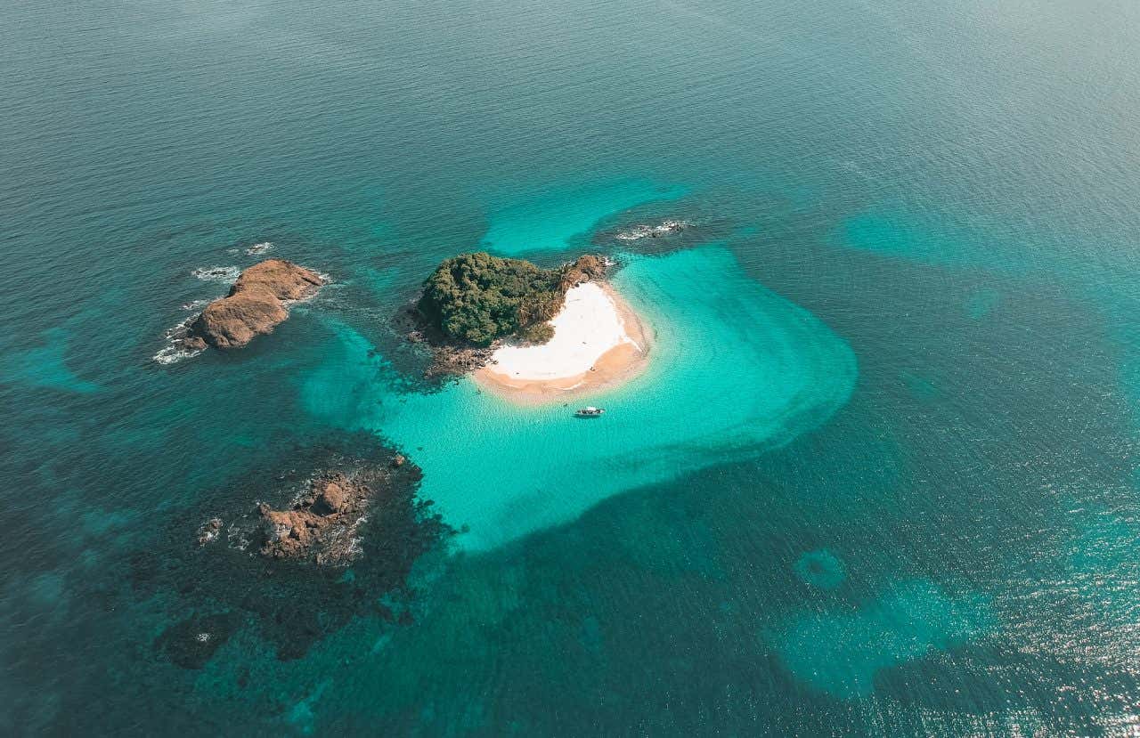 Uma ilha de areia branca e vegetação rodeada por águas turquesas
