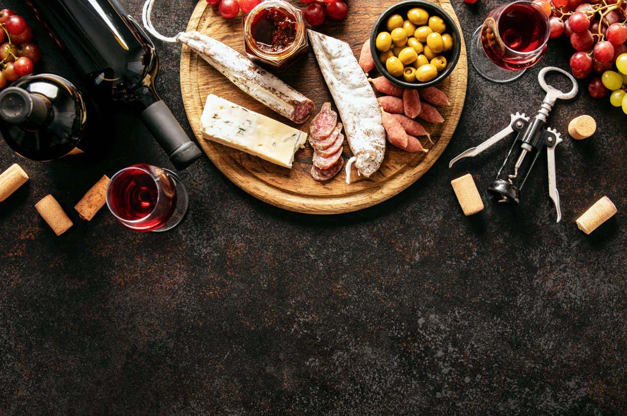 Plateau avec su saucisson, du vin de Bordeaux, des olives et du raisin