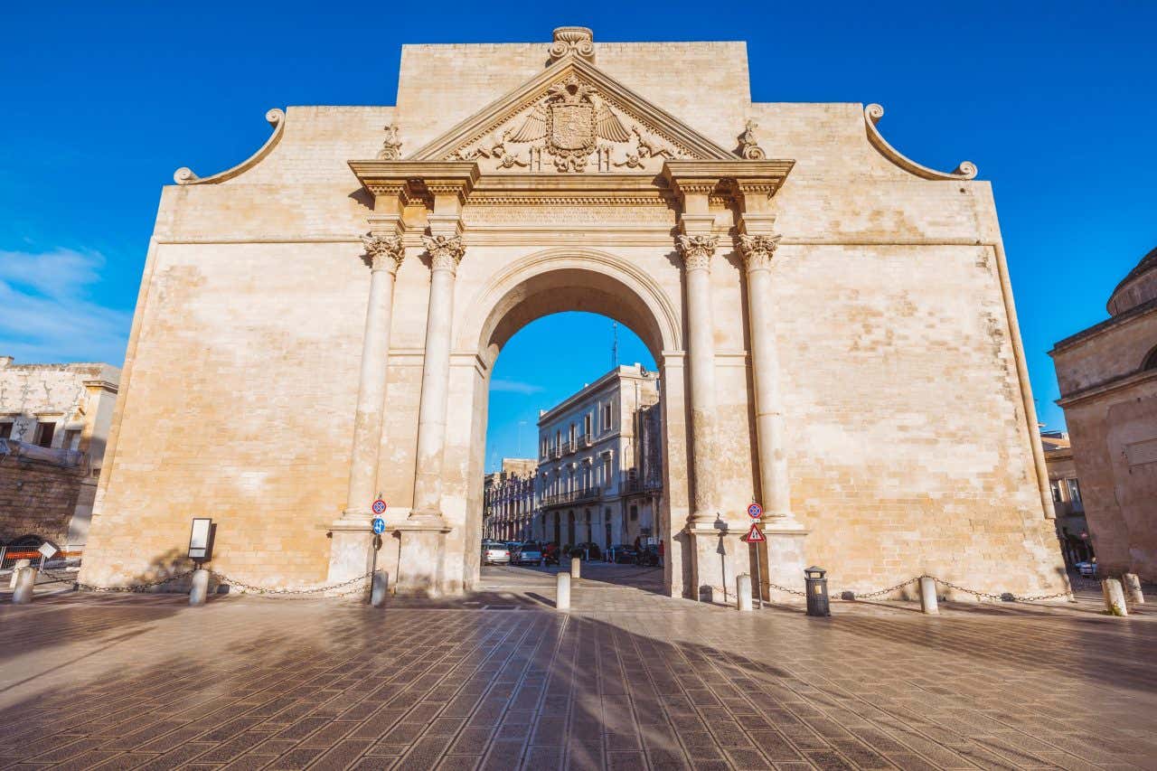 Un portale in pietra dorata in stile neoclassico, affacciato su una strada del centro storico di Lecce