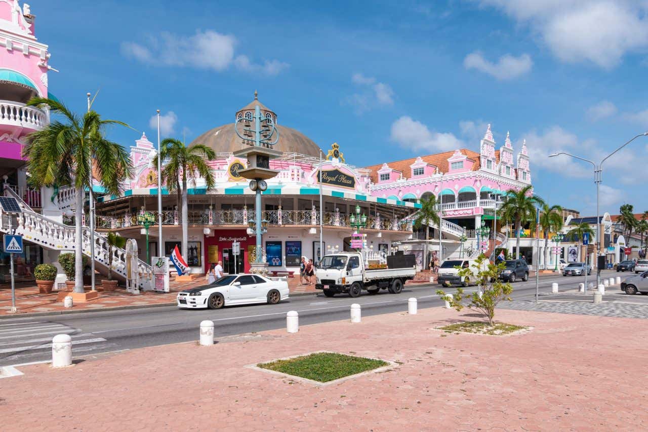 Uma rua de Oranjestad com edifícios coloniais coloridos e carros passando