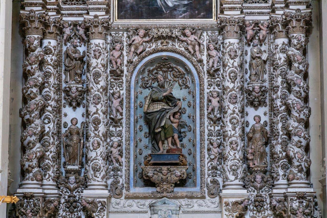 Un altare votivo di un santo in stile barocco, con al centro, su un piedistallo, la statua del santo, accerchiata da putti e colonne riccamente decorate