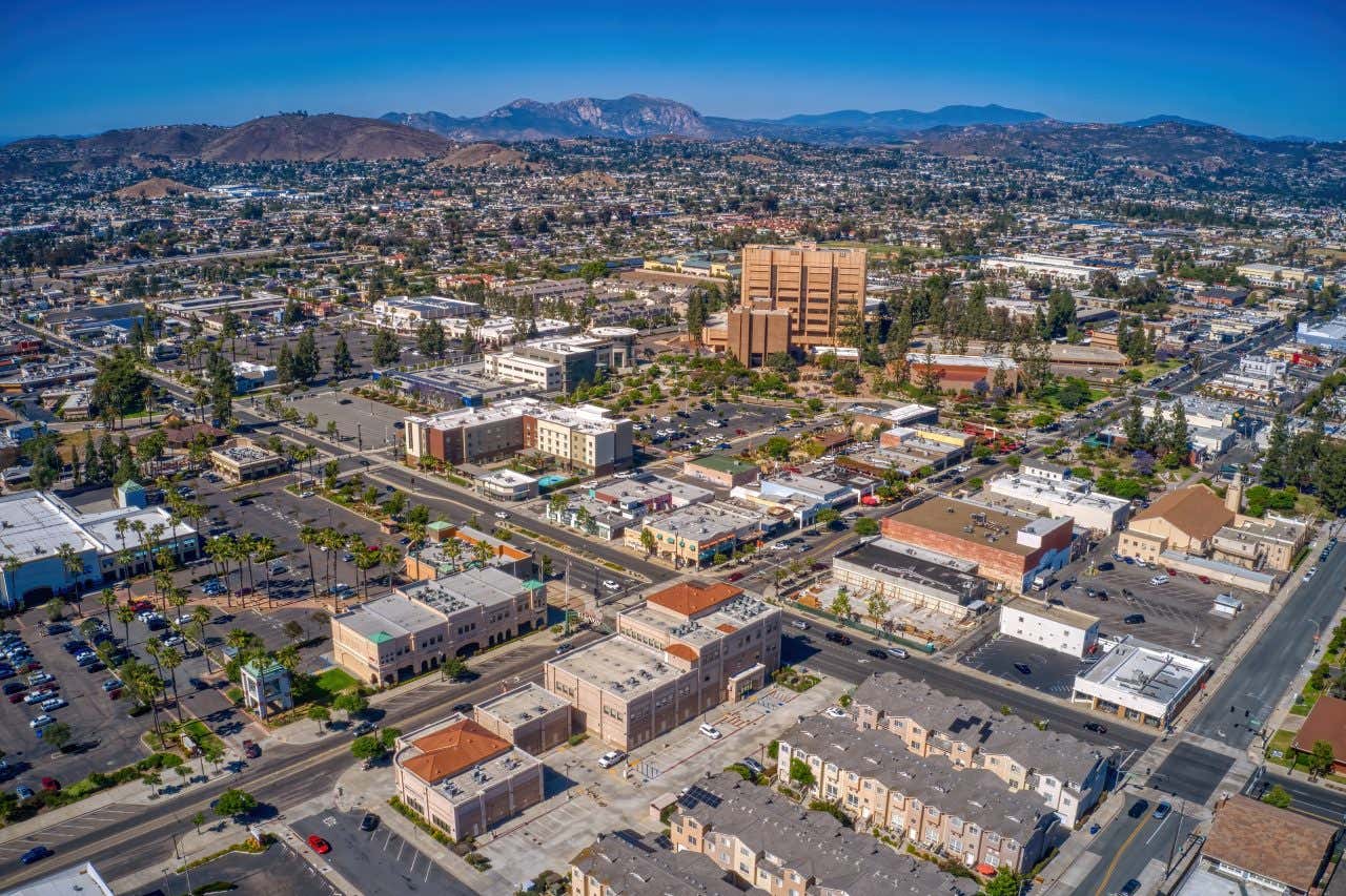 An aerial view of San Diego with a mountain view in the background and clear blue skies.