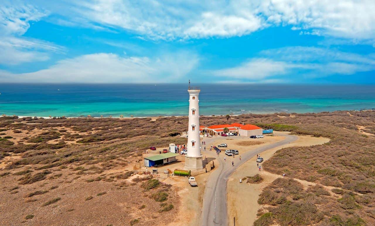 Farol Califórnia visto de cima rodeado pelo cenário semi-árido e com o oceano turquesa ao fundo