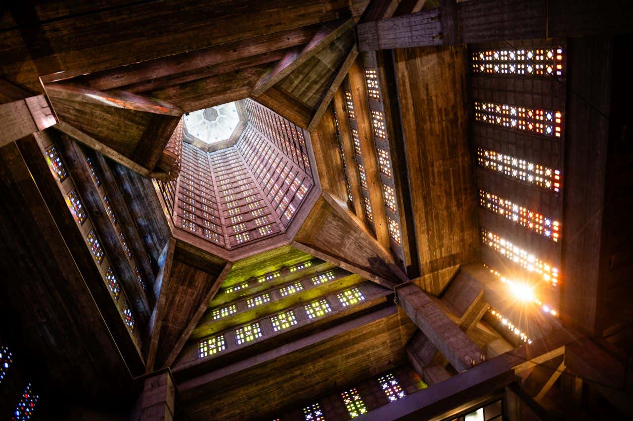 Interior view looking up at the hexagonal tower of St. Joseph's Church in Le Havre, with stained glass windows and natural light streaming through