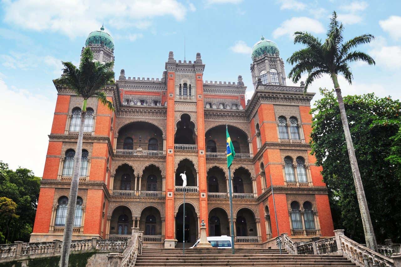 Fachada de tijolinhos do castelo Mourisco com uma bandeira do Brasil à frente