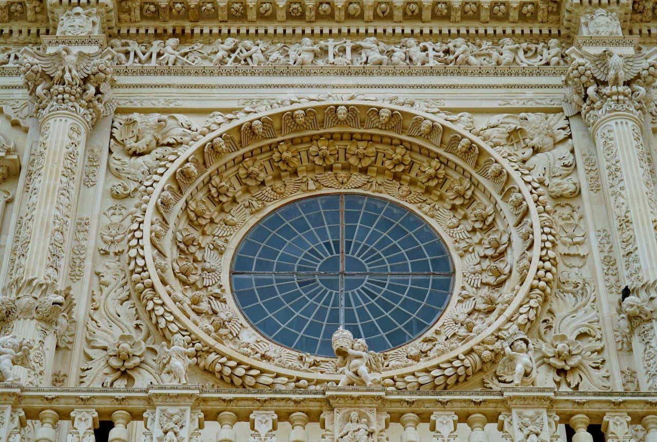 Un rosone in pietra riccamente decorato con motivi naturali e putti