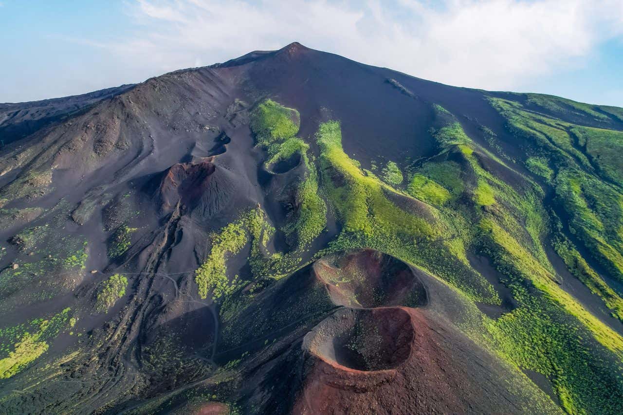 Vue sur deux des cratères de l'Etna, avec de la végétation sur ses flancs, une ascension à faire en Sicile