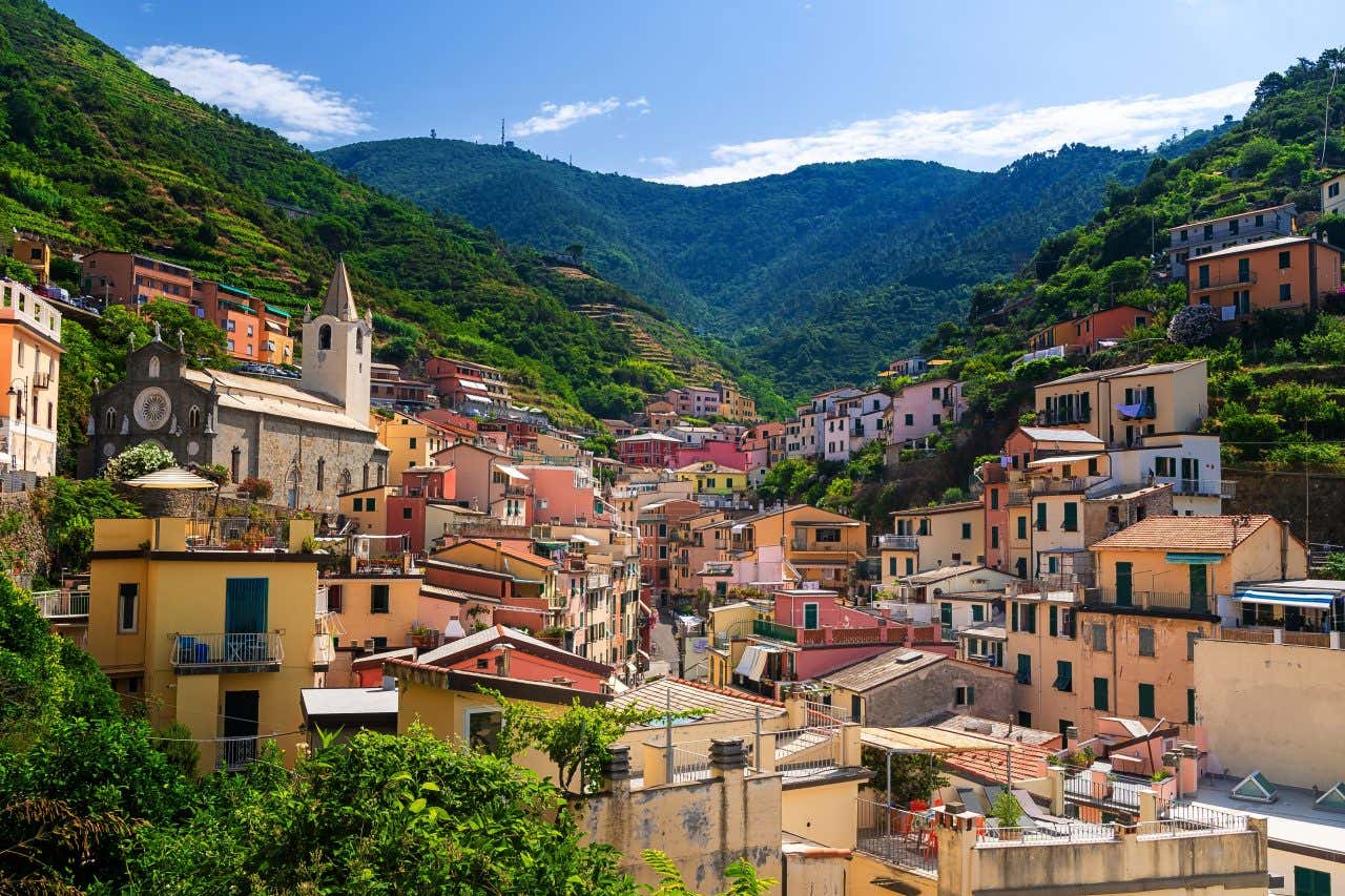 A town in Cinque Terre seen from the bottom of a mountain looking up with lots of densely packed homes.
