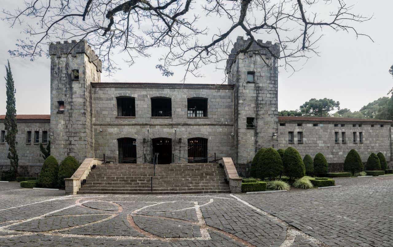 Fachada de pedra do Château Lacave em estilo medieval. Ruas de paralelepípedo com arbustos em volta do edifício.