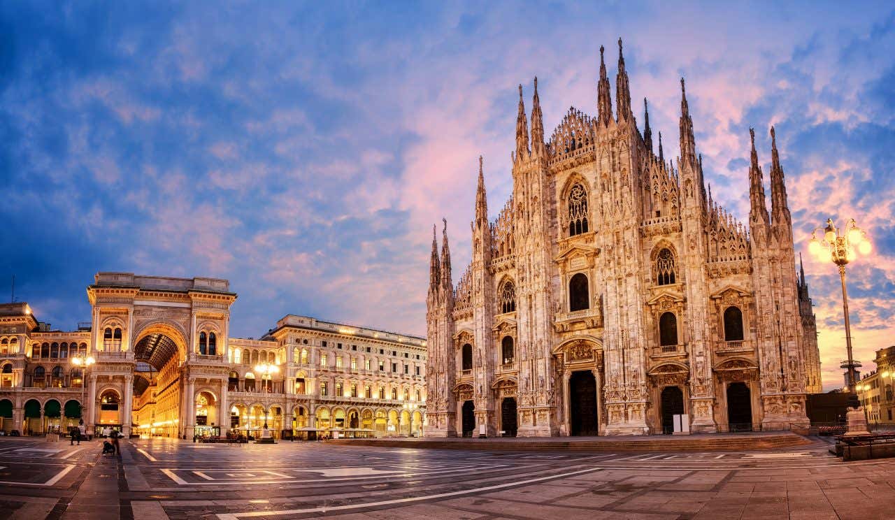 Il Duomo in Milan, seen from the square with no one in shot and blue and pink skies in the background.