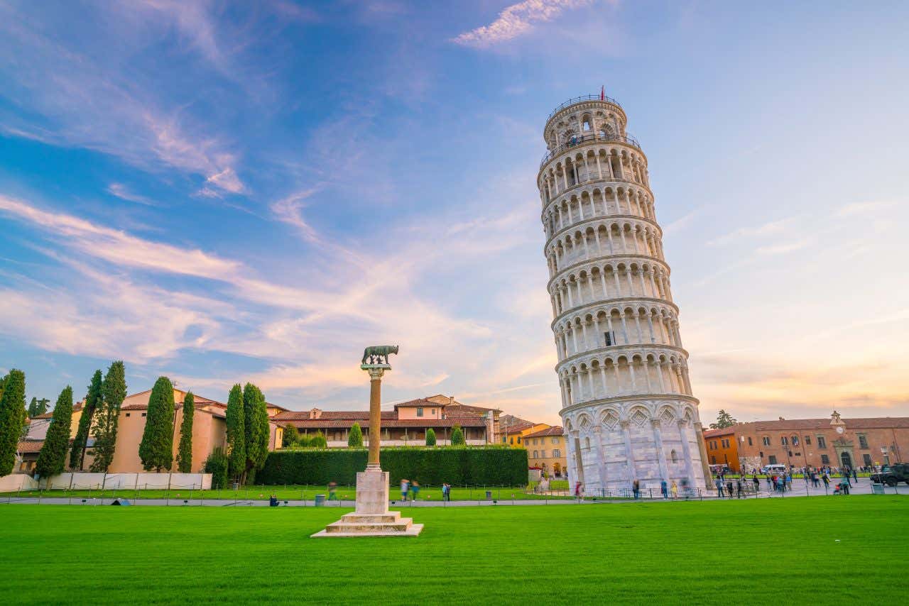 The Leaning Tower of Pisa seen from the ground with a blue and orange sky in the background.