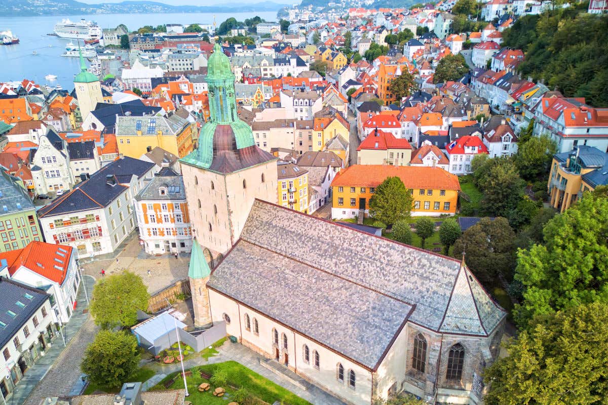 Vista aérea de la catedral de San Olaf de Bergen, con una gran torre y varias casas alrededor muy cerca del fiordo