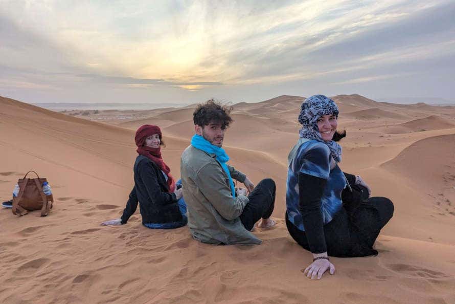 Tres chicos en las dunas del desierto de Merzouga al atardecer