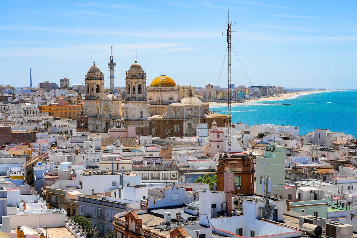 Vista aérea del centro histórico de Cádiz con varias casas, las dos catedrales y el mar en un día despejado