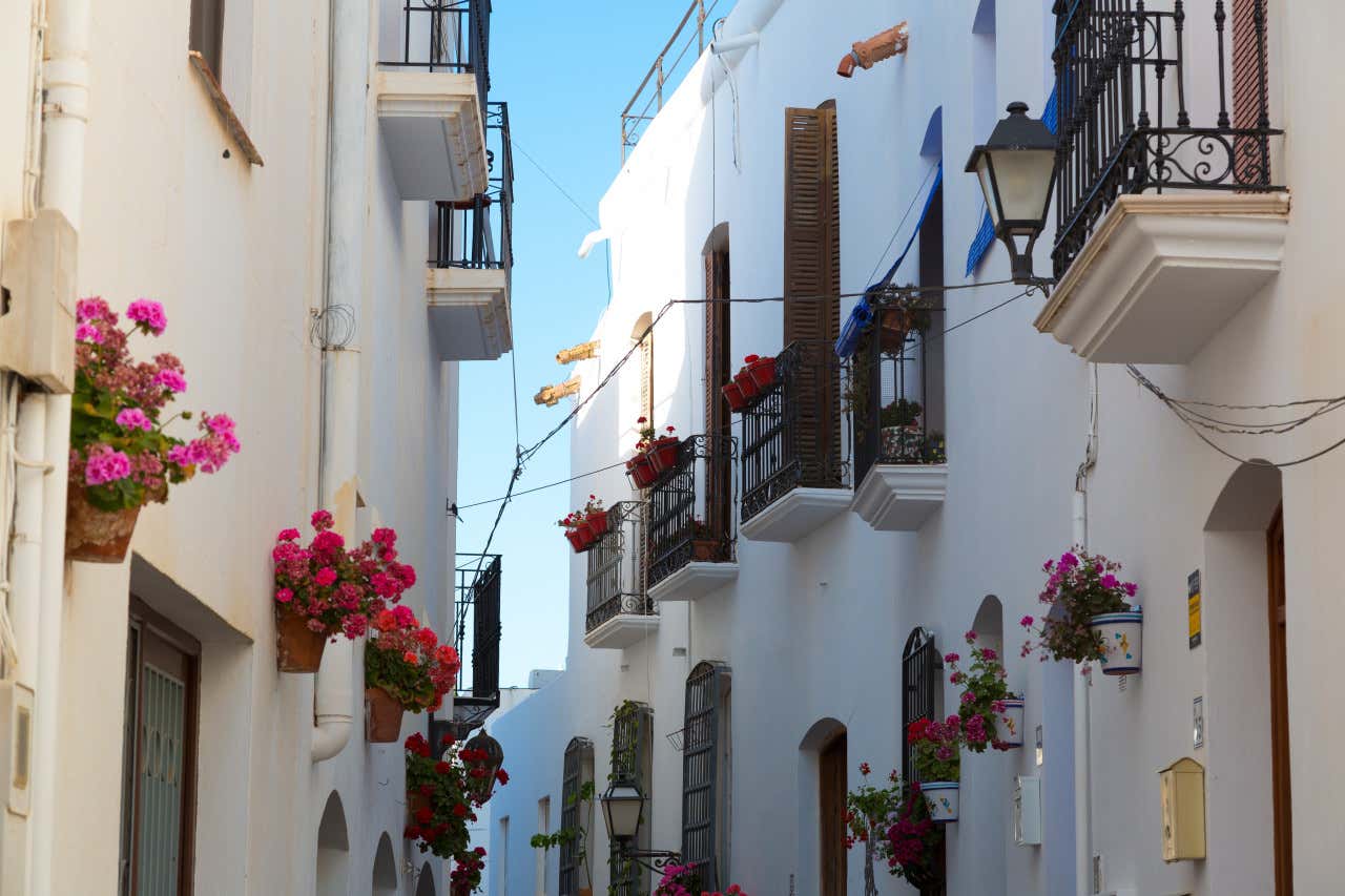 Calle con casas de fachadas blancas y balcones llenos de flores