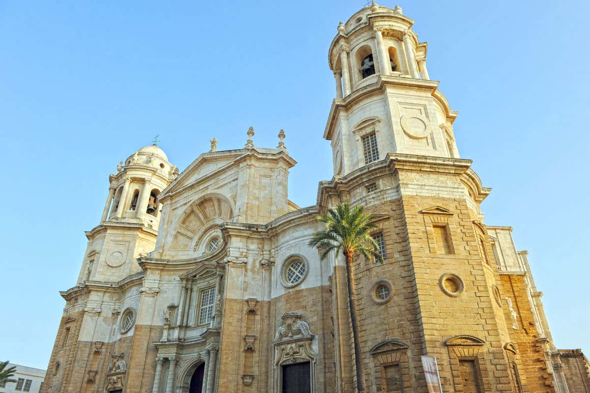 Fachada de la catedral de Cádiz, un edificio de piedra con una decoración sobria y dos torres