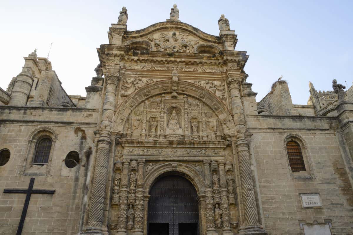 Fachada de una iglesia que destaca por su gran pórtico de decoración sobrecargada con numerosas esculturas de piedra