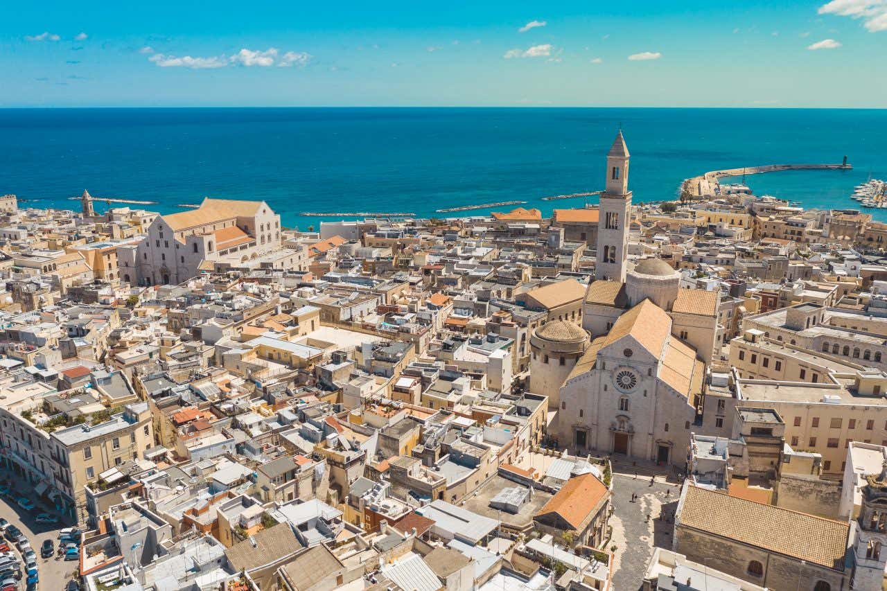 An aerial view of the historic center of Bari, with the sea in view, under a clear blue sky.