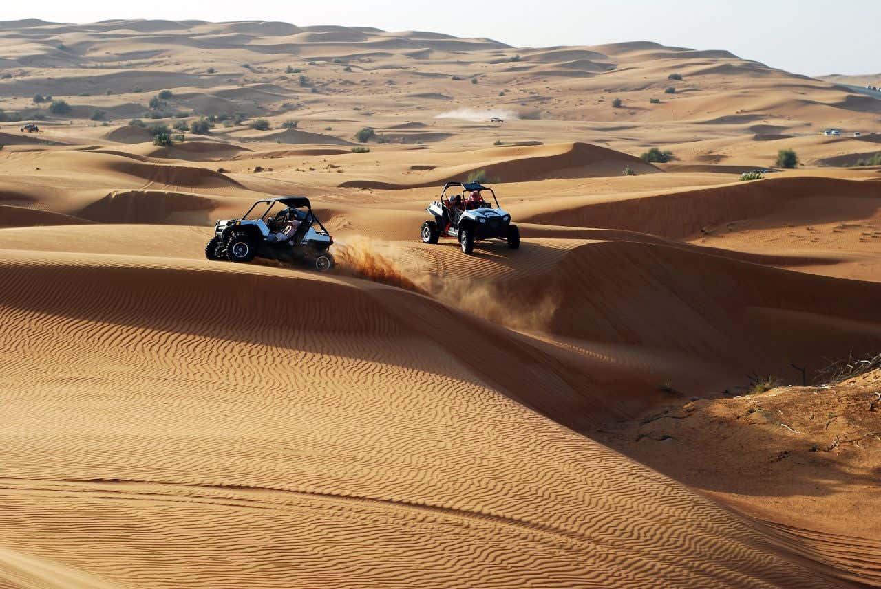 Dois buggies na paisagem desértica de areia e pouca vegetação