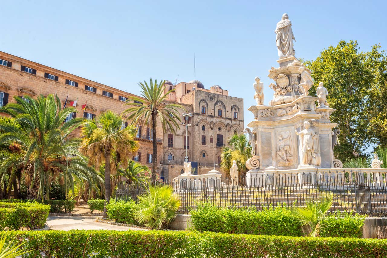 Uma estátua em primeiro plano e o Palácio Real dos Normandos ao fundo