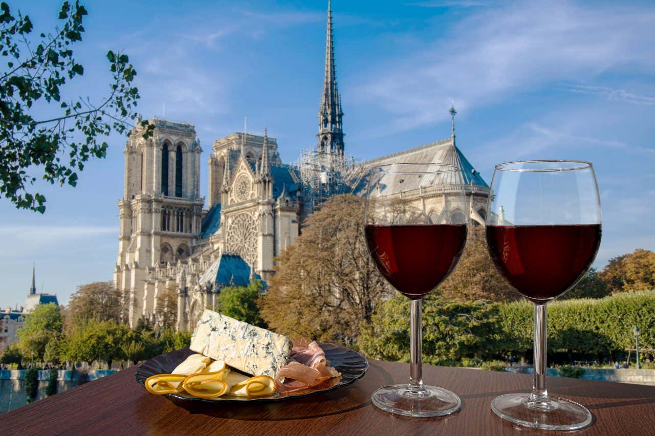 Deux verres de vin et une assiette de fromage et de charcuterie avec la cathédrale Notre-Dame en arrière-plan