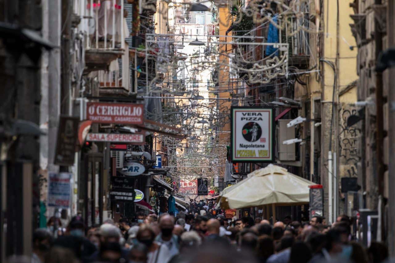 Spaccanapoli in Naples, with lots of people on the road and lights up above.