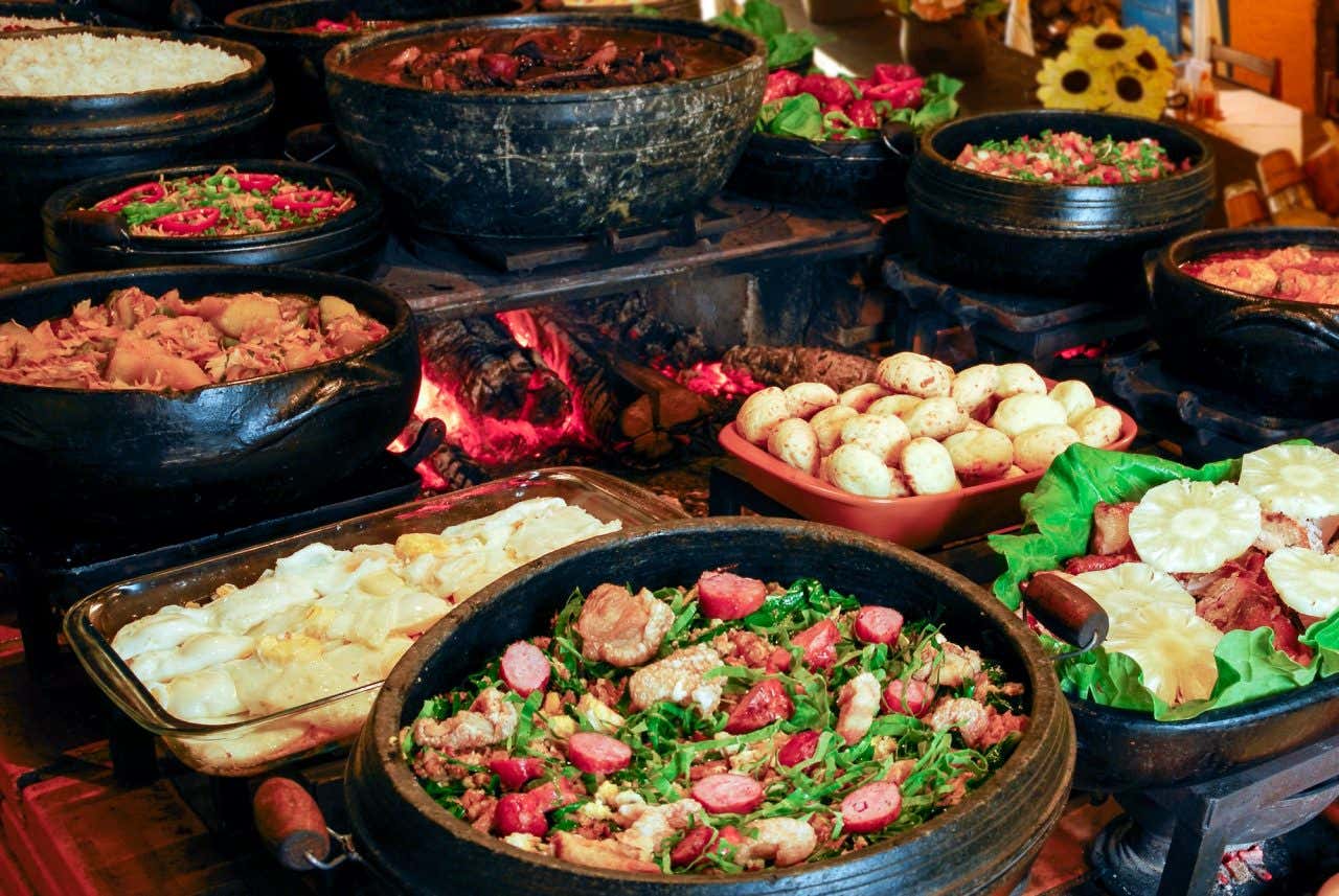 Mesa repleta de pratos mineiros, como feijão tropeiro, pão de queijo, carne de porco, feijoada, entre outros.