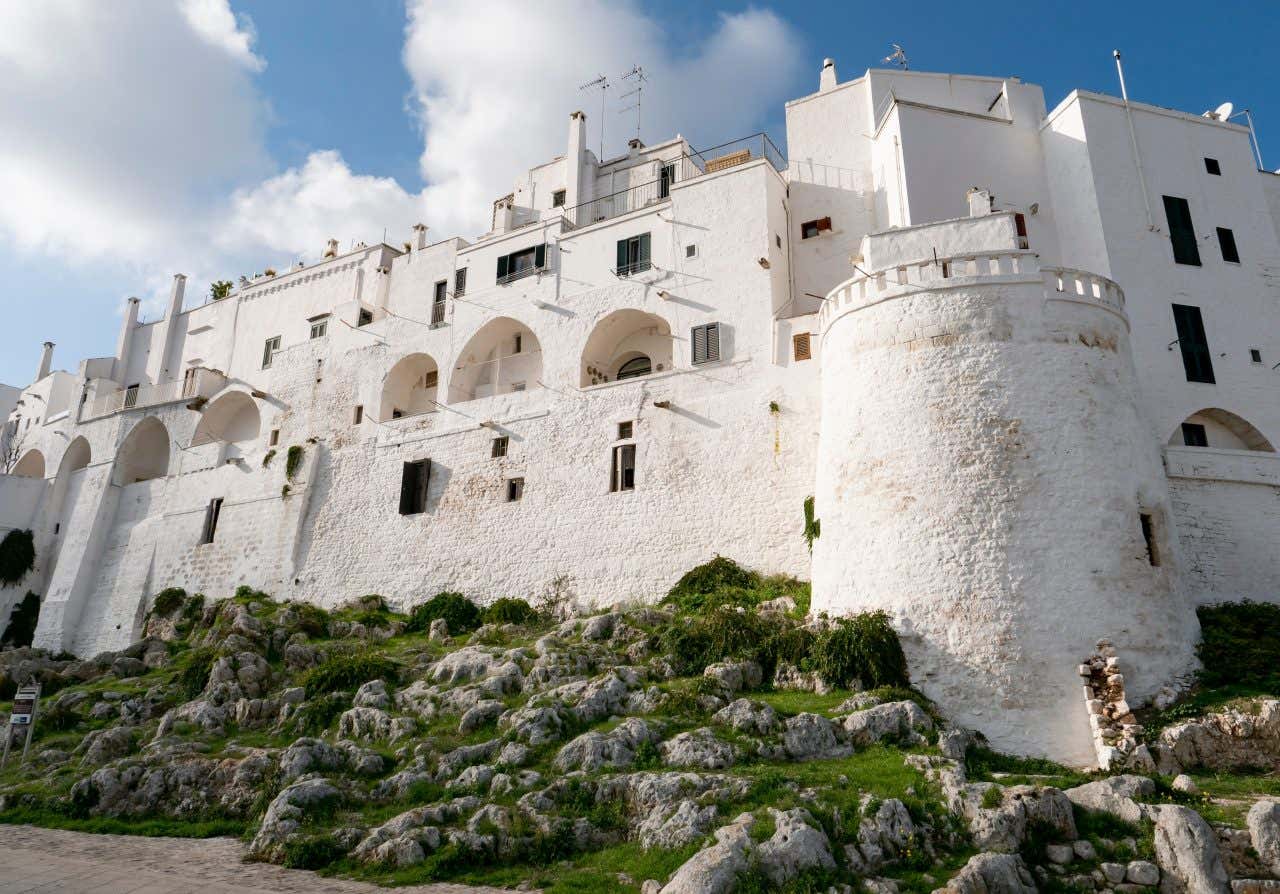 Le mura di cinta medievali del centro storico di Ostuni completamente ricoperte di calce bianca in una giornata di sole con qualche nuvola in cielo