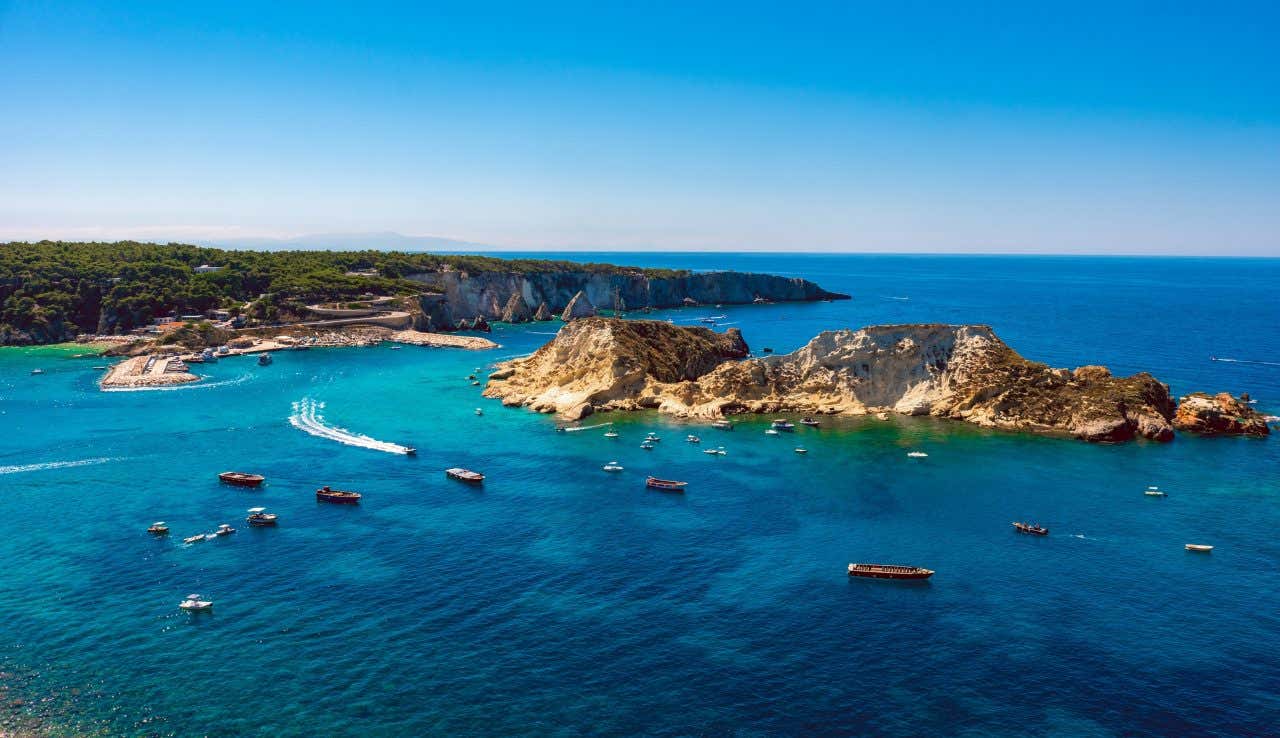 Veduta aerea delle Isole Tremiti con barche ormeggiate in acque turchesi e limpide, coste rocciose a picco sul mare e vegetazione mediterranea sullo sfondo