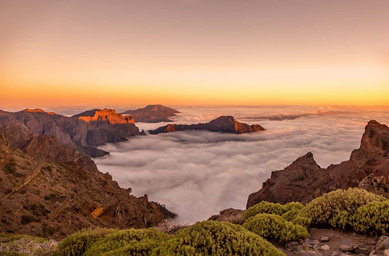vue sur le coucher de soleil depuis un sommet, avec les nuages en contrebas
