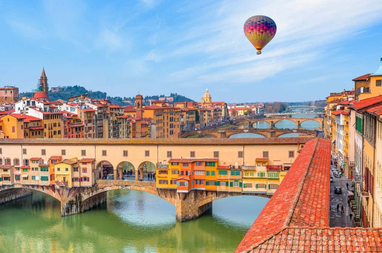 Vue sur le Ponte Vecchio de Florence, avec une montgolfière dans le ciel, un lieu où aller absolument en Italie