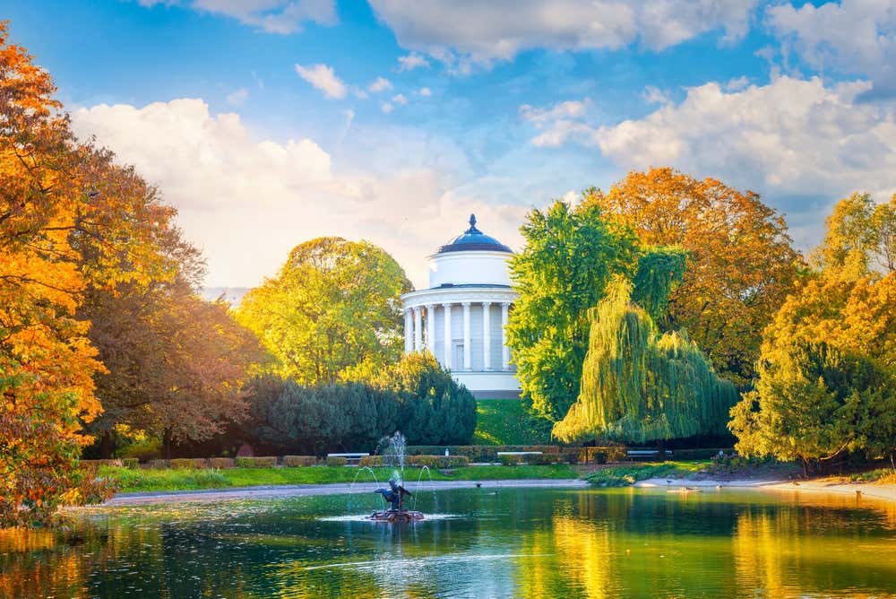 Una fontana circolare con un tempietto neo classico in cima a un collinetta accerchiato da alberi dalle foglie gialle, verdi e arancioni in autunno, nel Parco Sassone di Varsavia