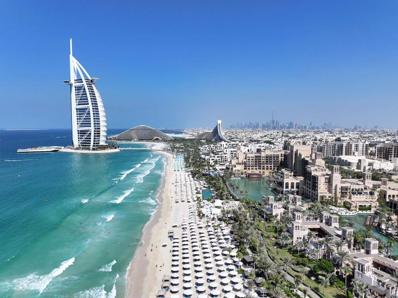 Foto aérea do icônico Burj Al Arab capturada na luz da tarde, mostrando sua majestosa arquitetura em forma de vela
