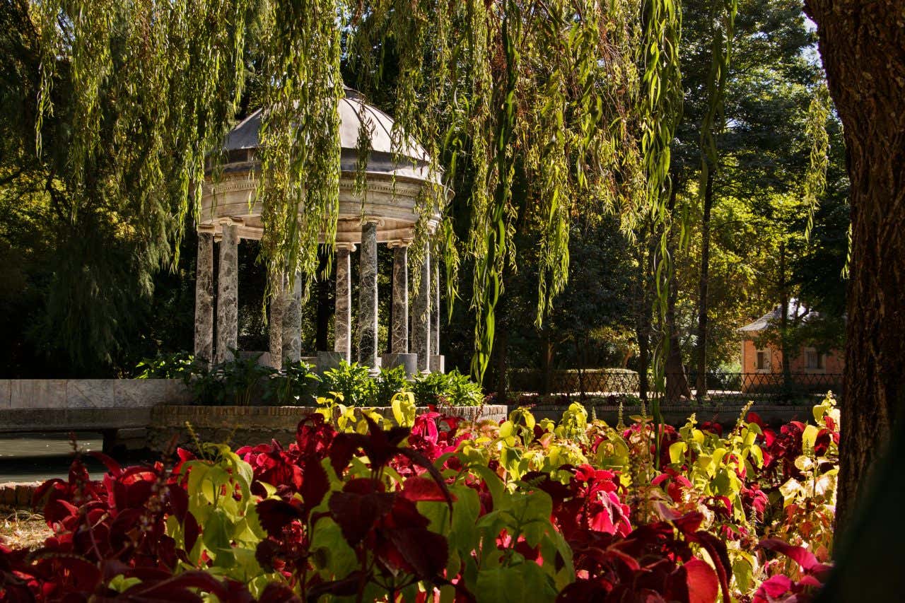 Plantes à feuilles rouges et vertes au premier plan, une rotonde à l'arrière, dans le jardin du Prince au palais royal d'Aranjuez, dans la région de Madrid