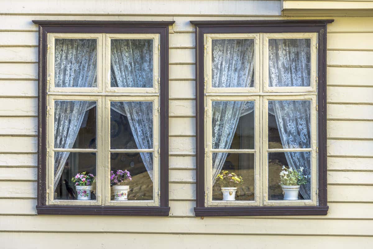 Una casa de madera pintada de color blanco y con dos ventanas