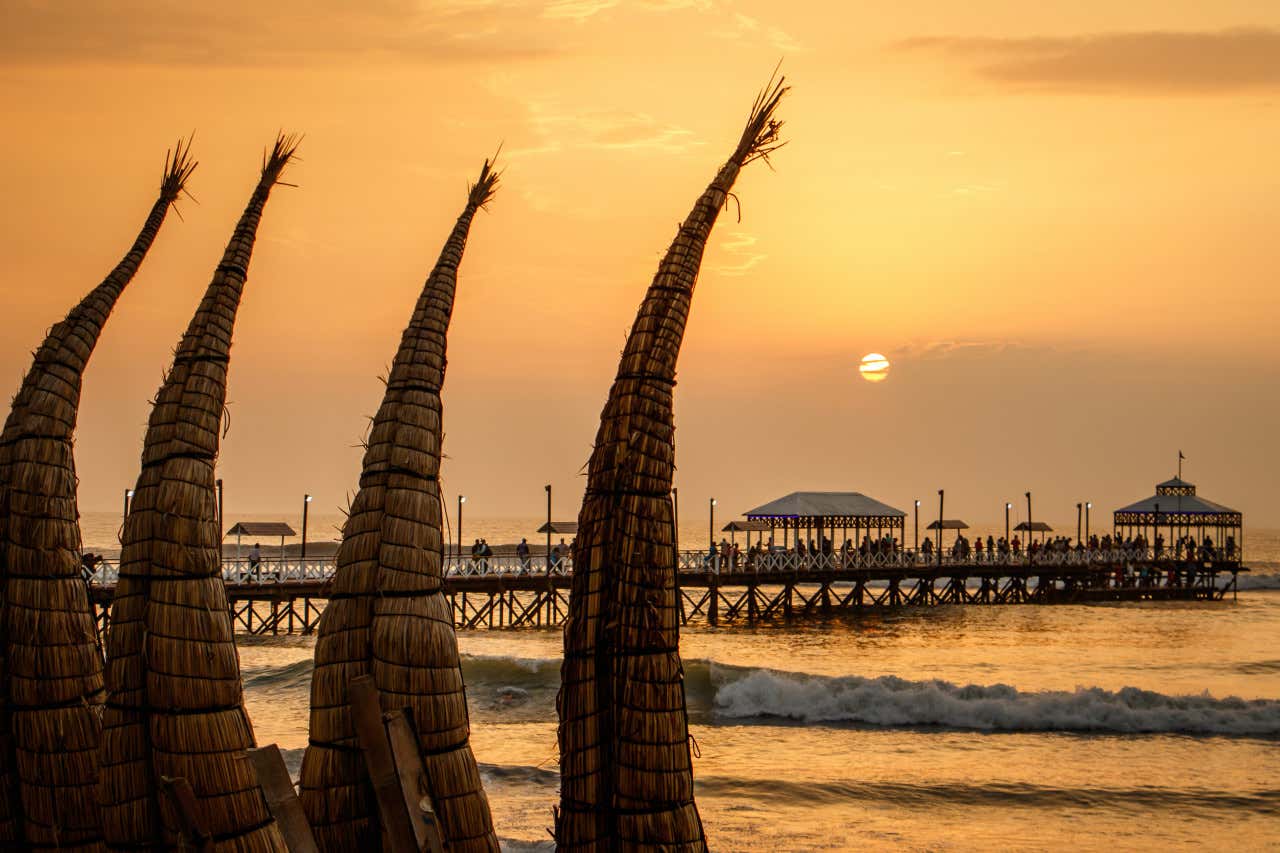 Atardecer en la playa de Huanchaco con caballitos de totora en primer plano