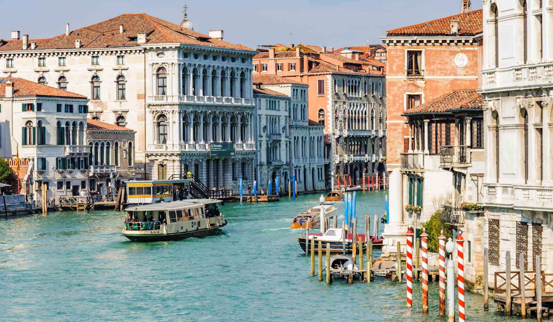 Panoramica di un canale di Venezia con diverse barche e un molo in una giornata soleggiata