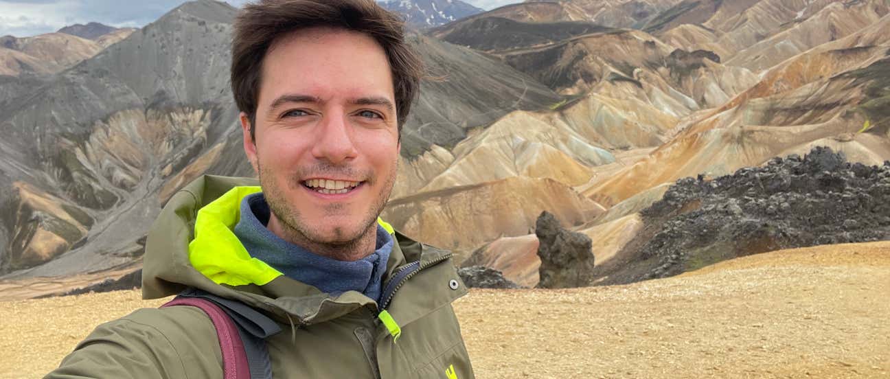 Un hombre se hace un selfie con unas montañas ocres de fondo