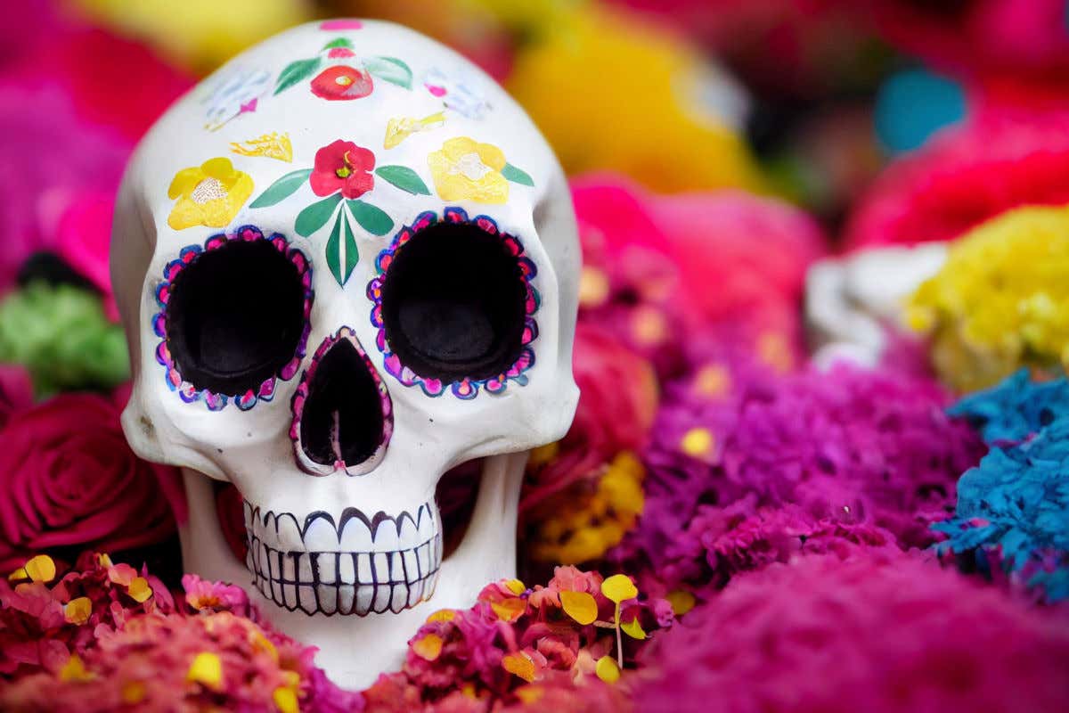 Una calavera típica del Día de los Muertos en México rodeada de flores hechas con papel