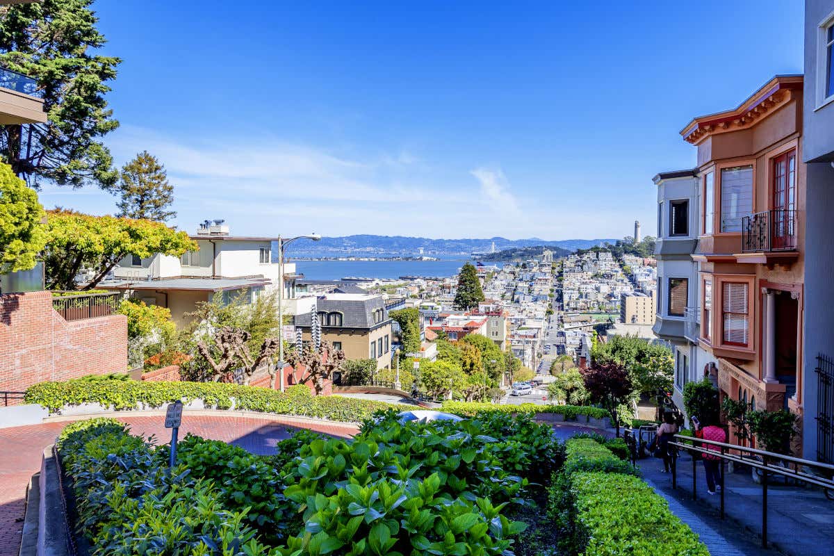 Varios turistas bajando por unas escaleras que rodean las curvas de la calle Lombard Street de San Francisco