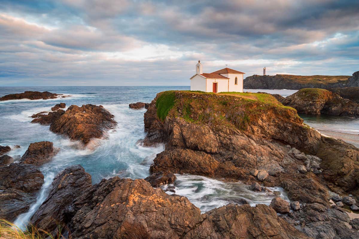 Una pequeña ermita en primera línea del mar rodeada por pequeños riscos en la Costa da Morte