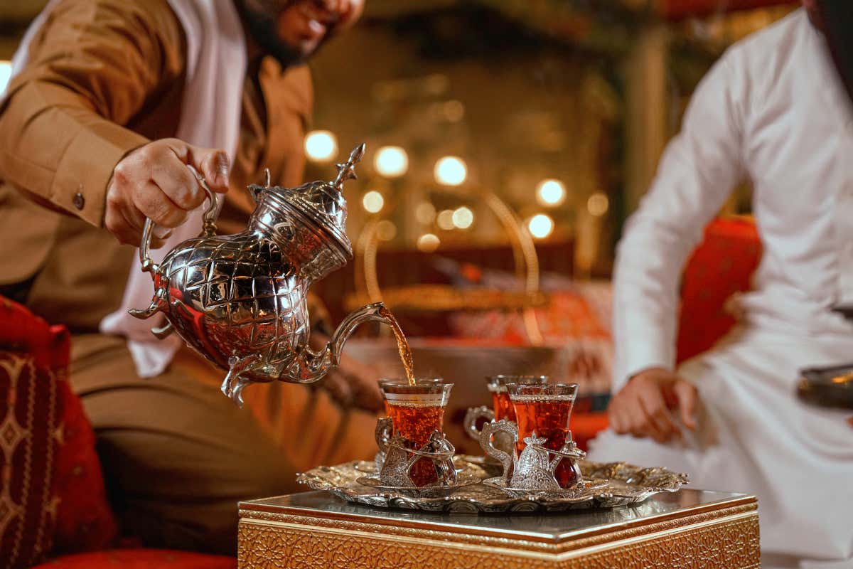 Un hombre vierte té en una taza