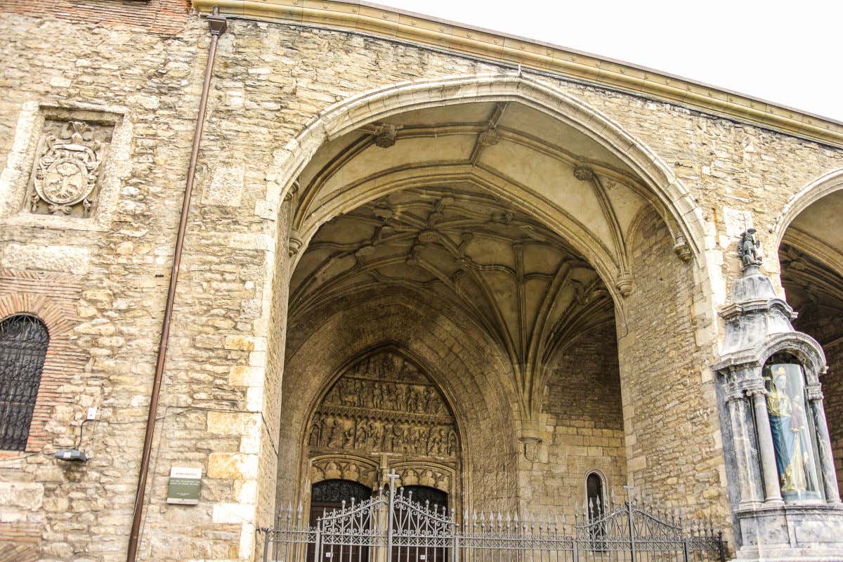 Fachada de una iglesia de piedra con un gran pórtico con esculturas y una imagen de una virgen policromada