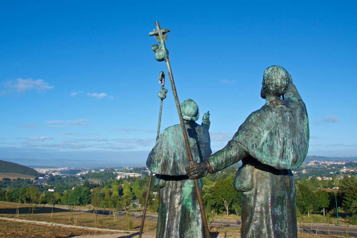 Esculturas de bronce de dos peregrinos ubicadas en la cima de una colina