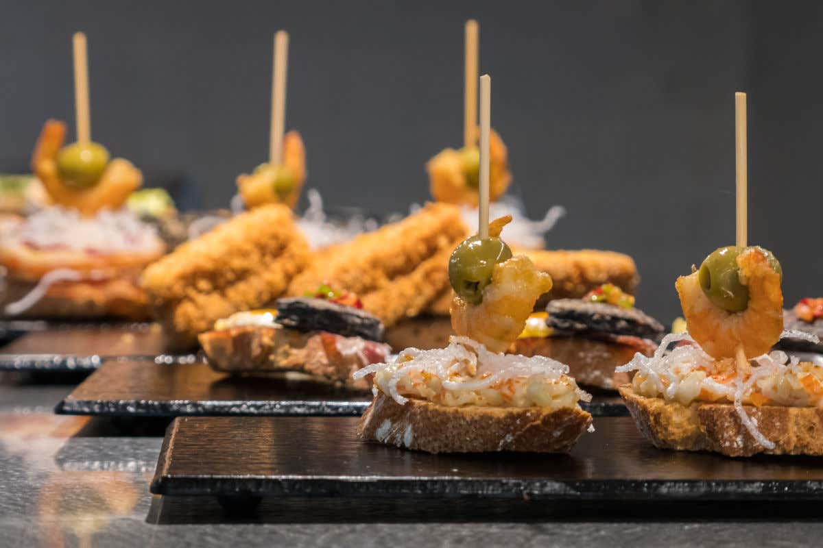 Varias bandejas de pizarra negra con pequeños pintxos, es decir tapas típicas del País Vasco compuestas por una pequeña porción de pan con gambas y otros manjares