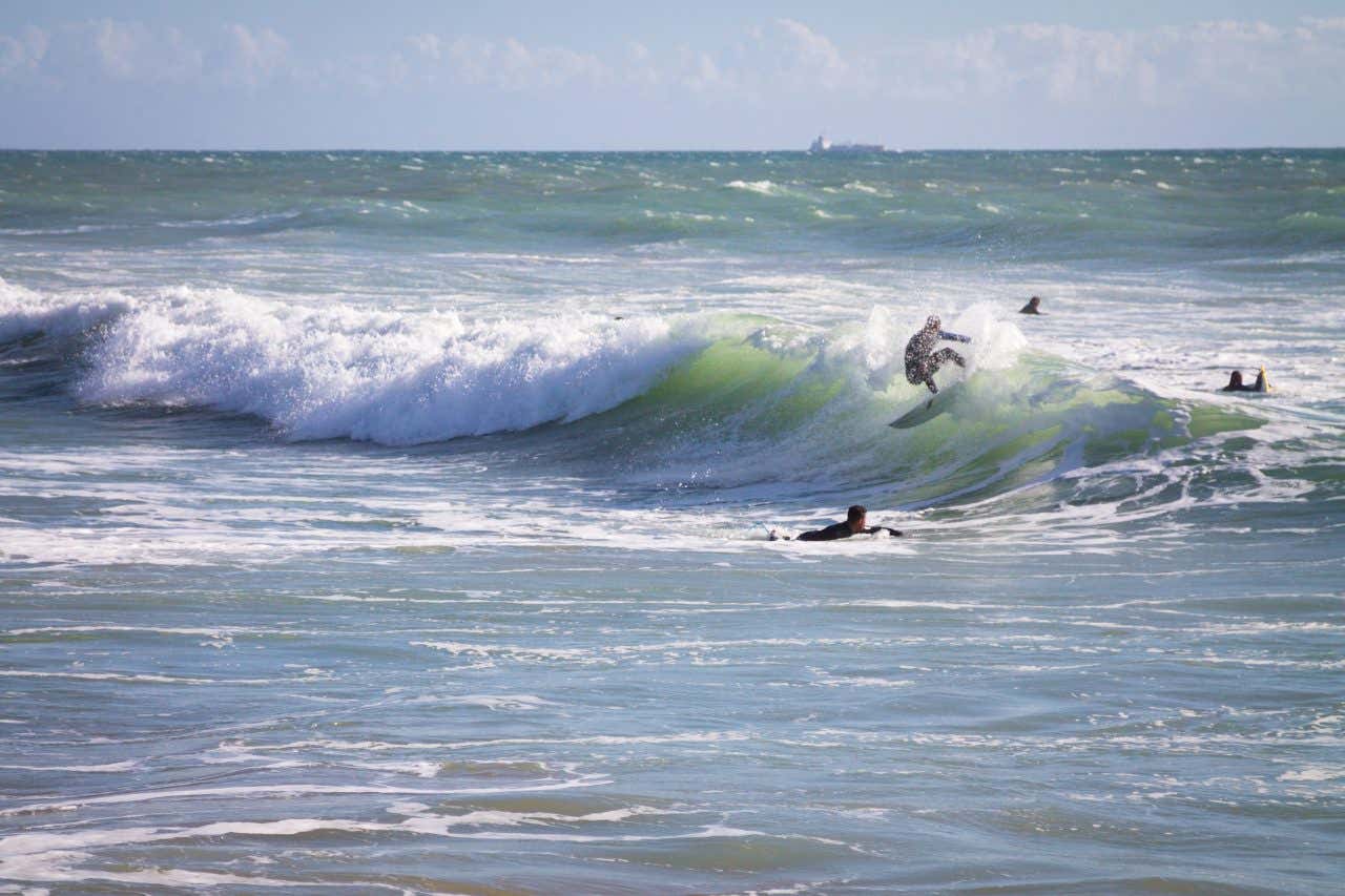 Surfeurs sur une vague à Agadir, une activité à faire lors de votre séjour
