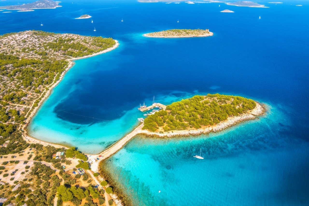 An aerial view of the Blue Lagoon in Croatia, with turquoise and deep blue waters along the white sand beaches.